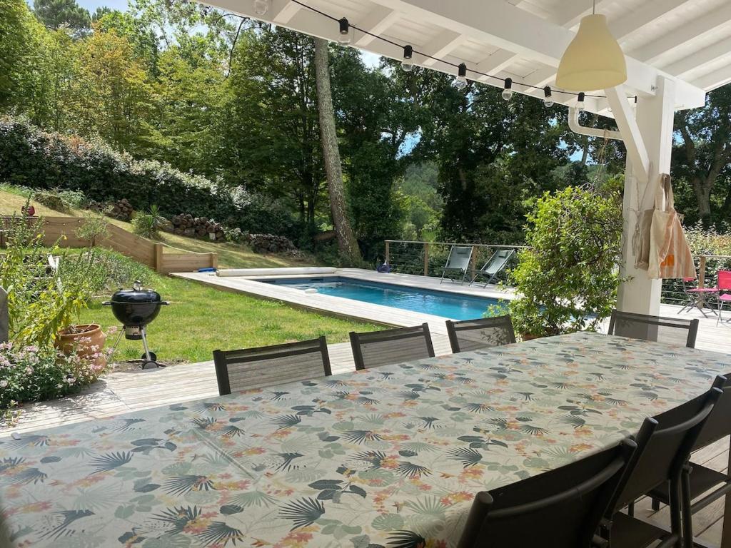 un patio avec une table et des chaises et une piscine dans l'établissement Villa au calme piscine chauffée dix couchages, à Seignosse