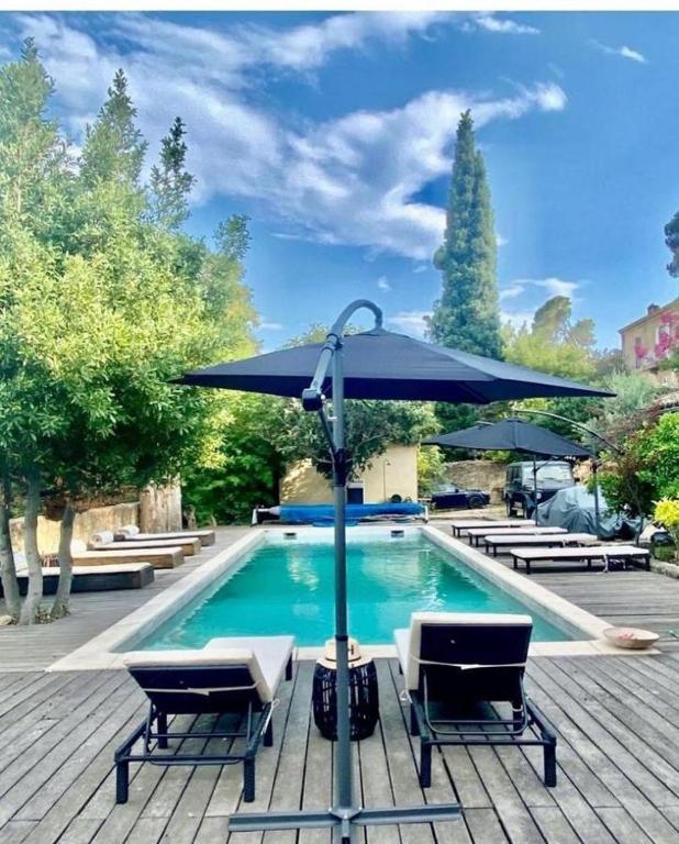 une piscine avec deux chaises et un parasol dans l'établissement Villa de pont du Gard, à Remoulins