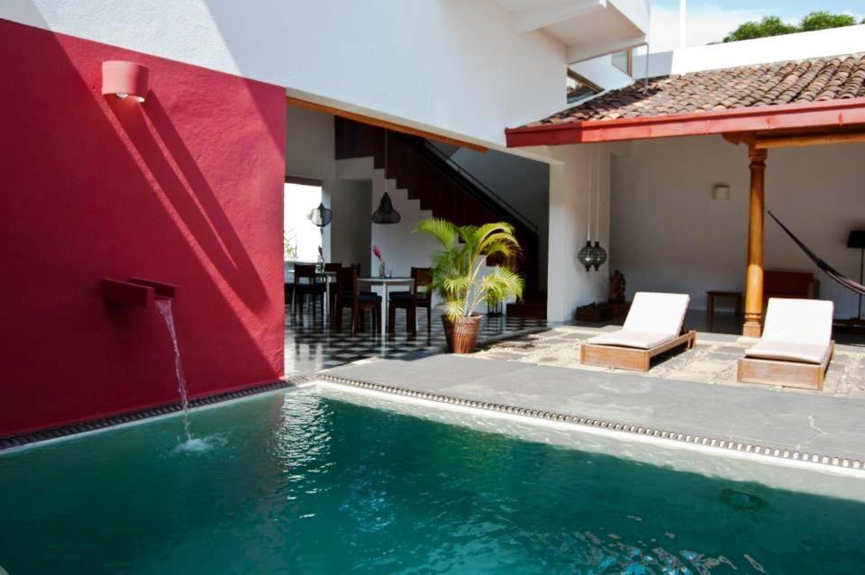 Los Patios Hotel Granada في غرناطة: منزل به مسبح بجدار احمر