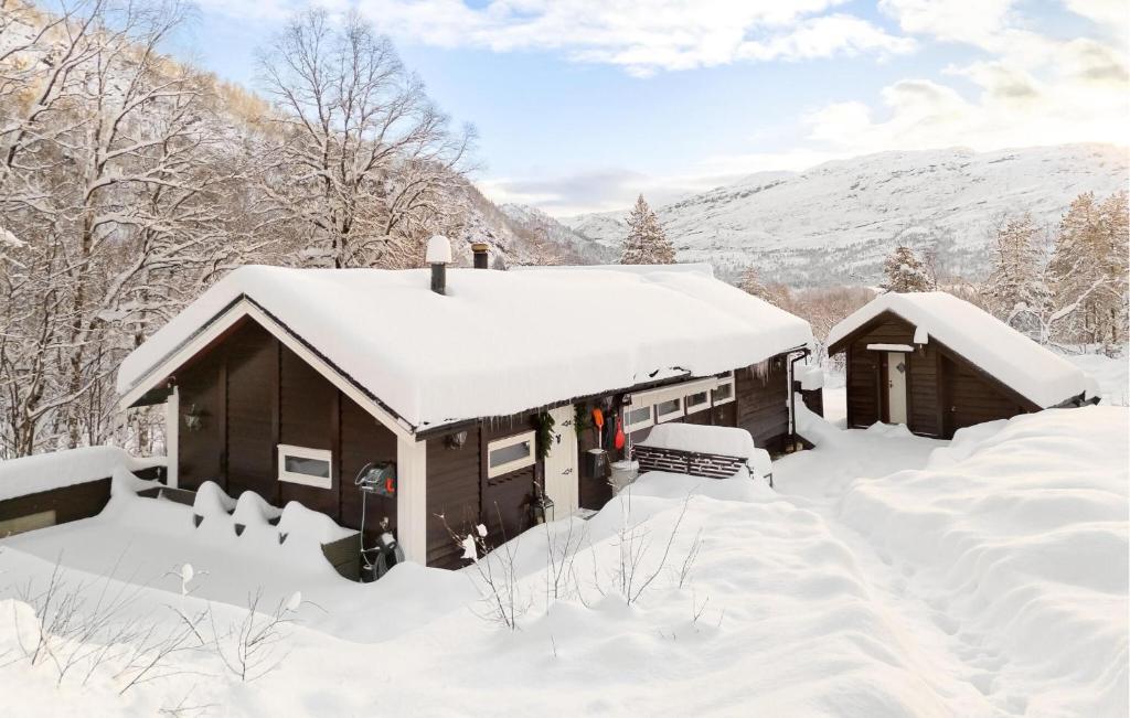 a cabin covered in snow with mountains in the background at 3 Bedroom Amazing Home In Tysse in Tysse
