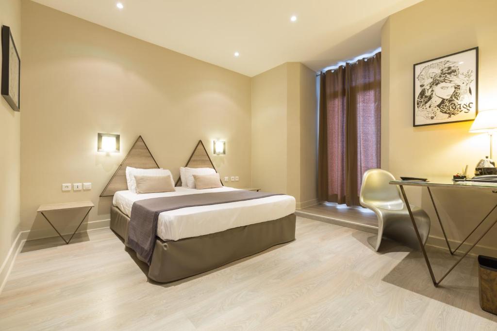 a hotel room with a bed and a desk at Hôtel Amirauté in Toulon