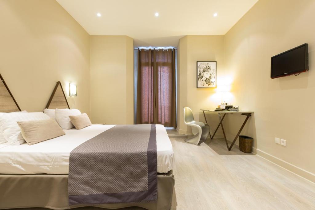 a bedroom with a bed and a desk and a television at Hôtel Amirauté in Toulon