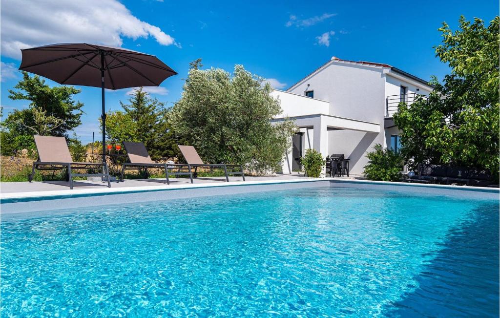 a swimming pool with two chairs and an umbrella at Villa Black Wood in Zadar