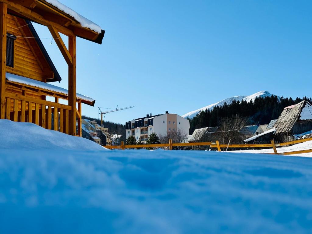 a house with snow on the ground next to a building at Alfa Omega Žabljak in Žabljak