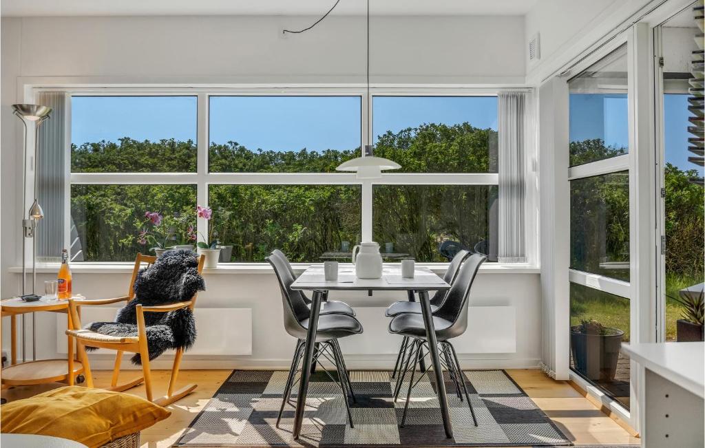a dining room with a table and chairs and windows at Fanø Bad, Lejl 15 in Fanø