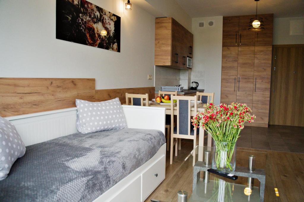 a living room with a couch and a table with flowers at Apartamenty Galicja Zator in Zator