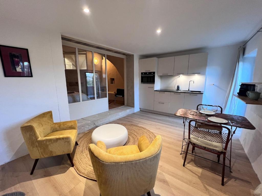 un salon avec des chaises et une table et une cuisine dans l'établissement Près d'Avignon, studio de charme avec vue, à Villeneuve-lès-Avignon