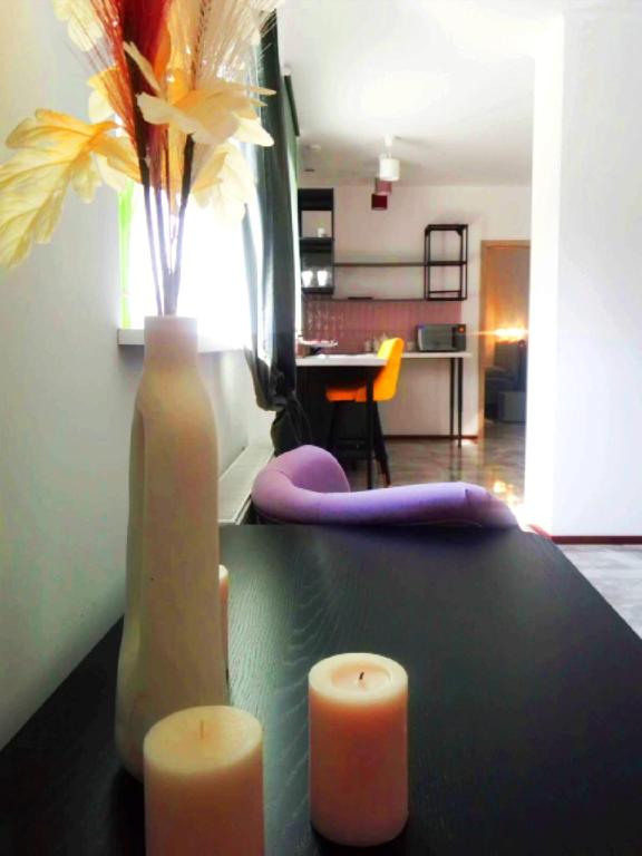 a table with two candles and a vase with flowers at Vista premium apart in Choszczówka