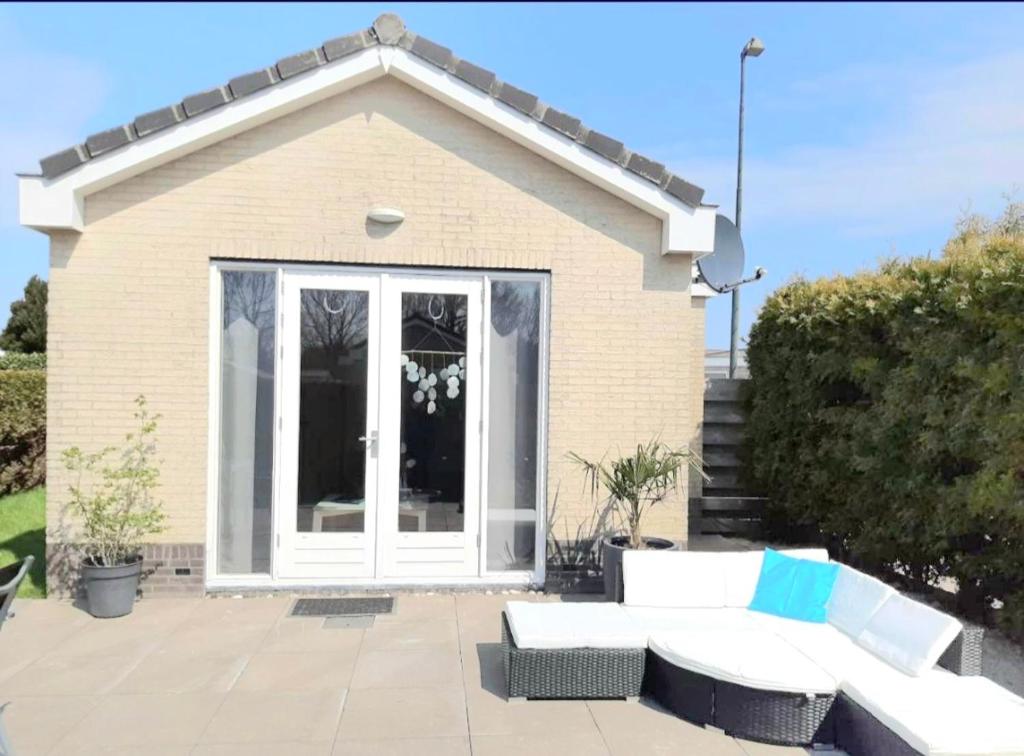 a patio with a white couch and a house at Huisje Finn, met grote tuin en veel privacy in Dirkshorn