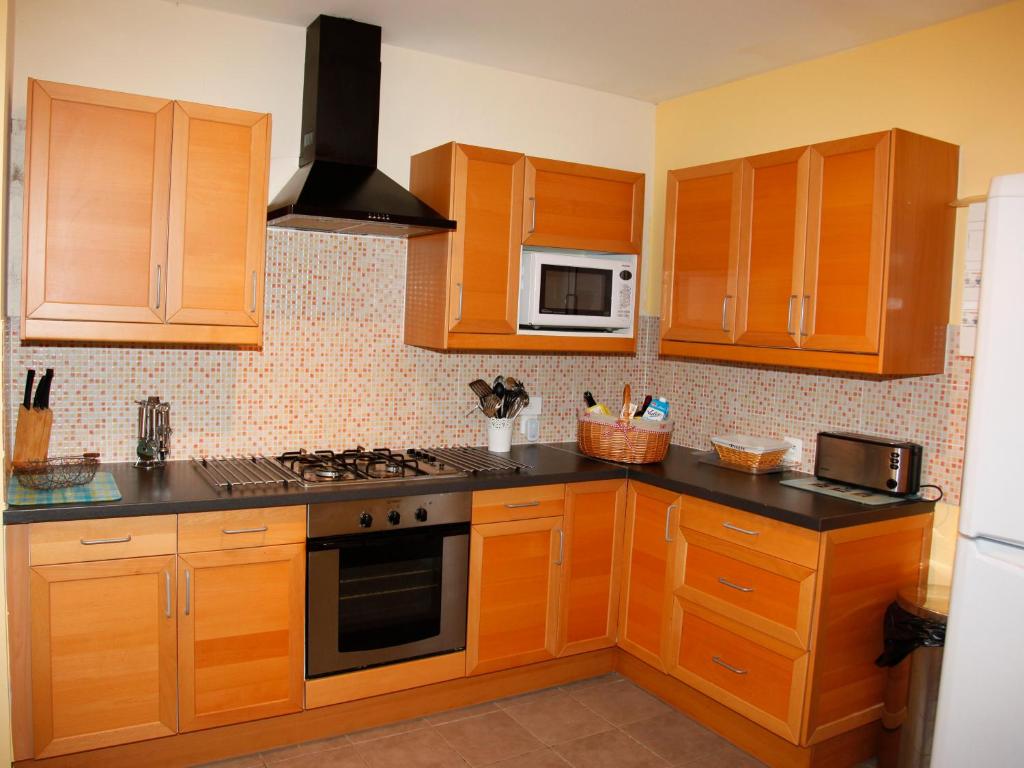 une cuisine avec des armoires en bois et un four à plaques de cuisson dans l'établissement Les Gîtes Champêtres Walnut cottage, à Sainteny