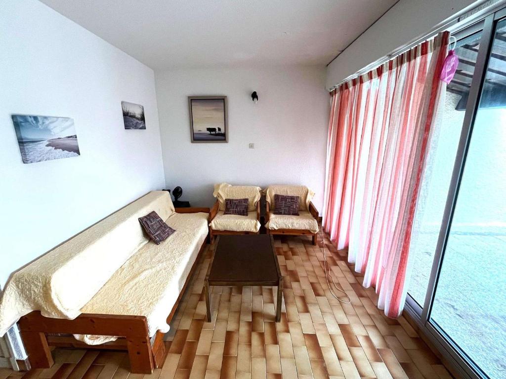 Cette chambre comprend deux lits et une grande fenêtre. dans l'établissement Charmant T3 familial - Front de mer, terrasse, parking, proche plage et activités, tout confort - FR-1-607-199, au Cap d'Agde