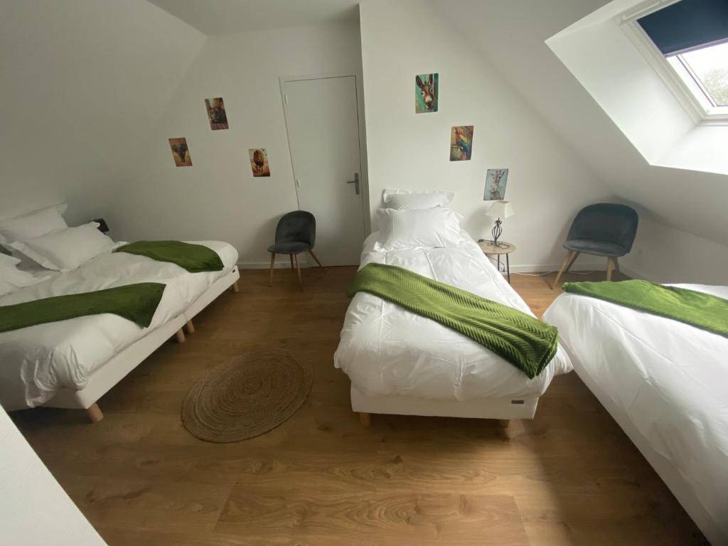 a bedroom with two beds and two chairs in it at Duplex l Auvetia 150 m circuit 24 h in Arnage