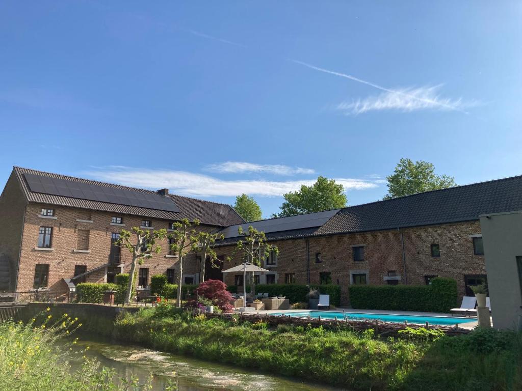 a building with a swimming pool next to a river at De Ruttermolen in Tongeren