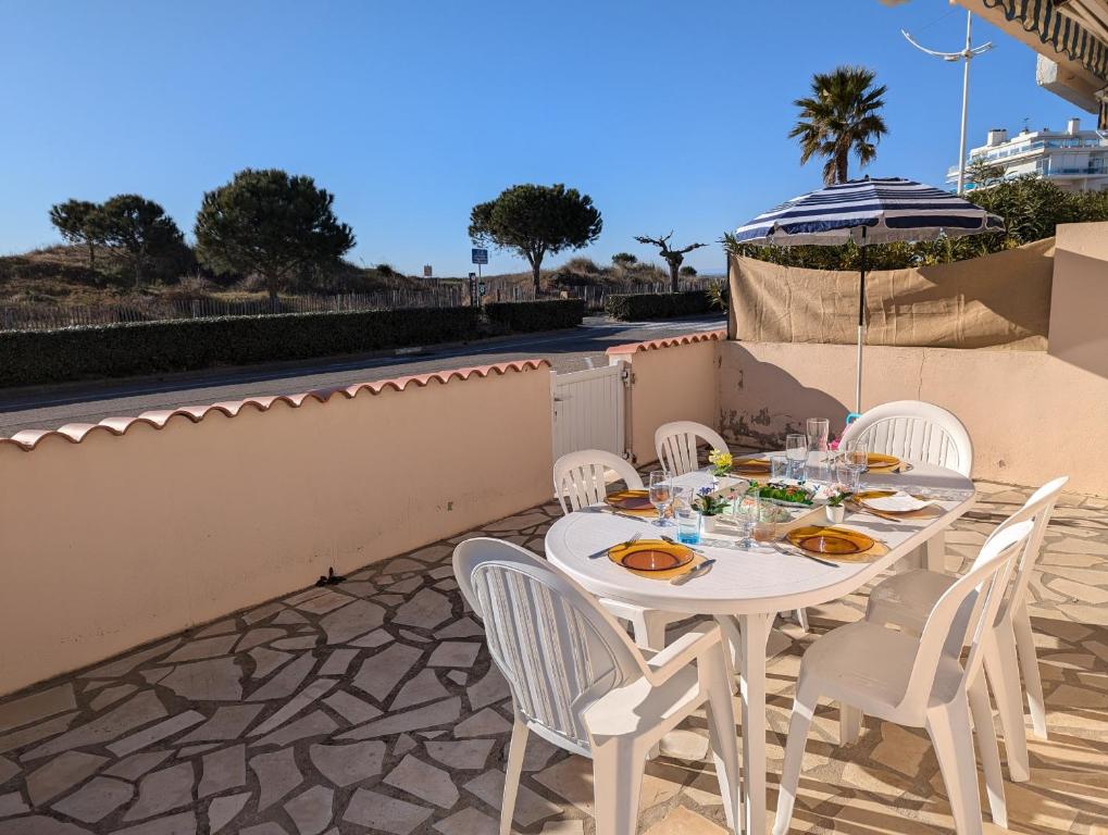 une table blanche et des chaises sur une terrasse dans l'établissement Sol-y-Days Altitude Zéro en première ligne face à la plage, au Grau-du-Roi