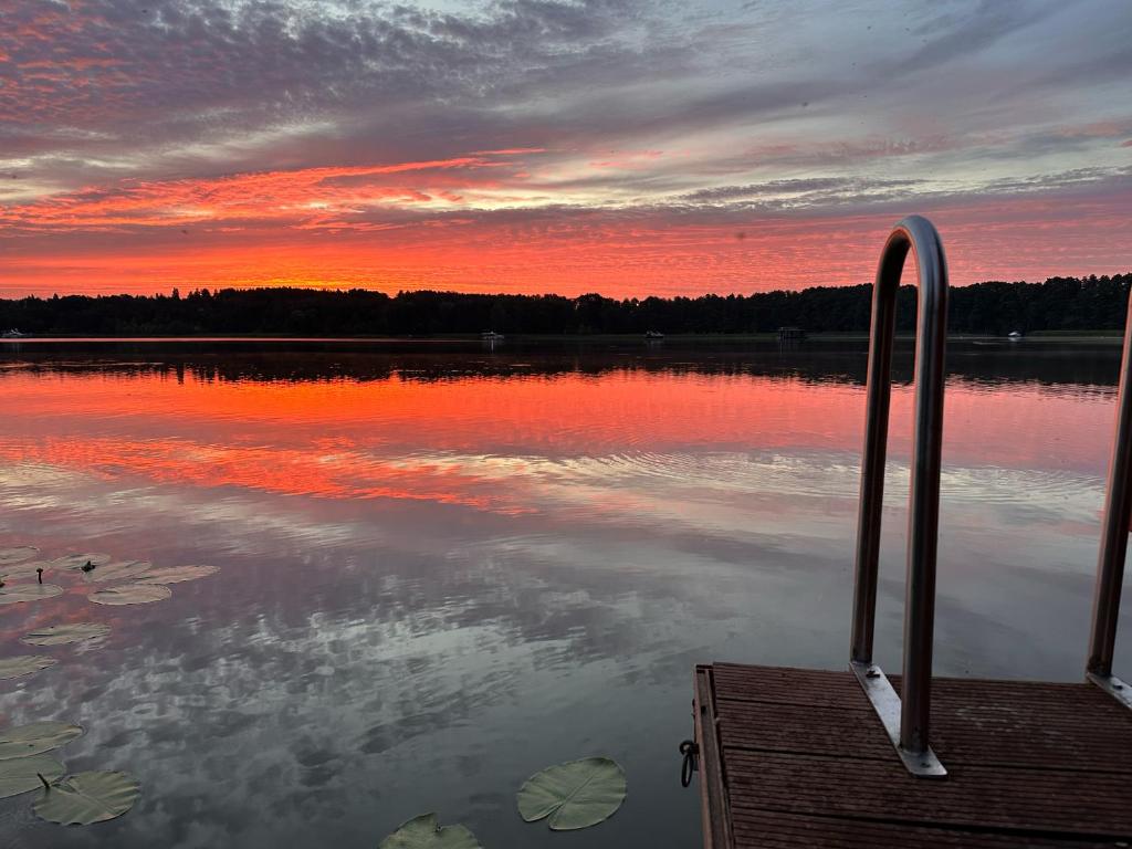 a sunset on a lake with a wooden dock at Ferienhaus Kranich am Pälitzsee in Rheinsberg