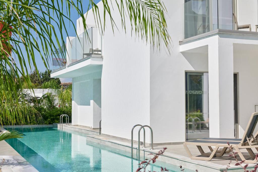 a villa with a swimming pool and two lounge chairs at Atlantica Sungarden Park in Ayia Napa