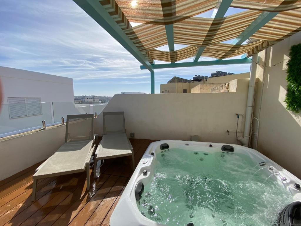 un jacuzzi sur un balcon avec deux chaises dans l'établissement Amazing 4-bedroom Sliema Town House with Jacuzzi, à Sliema