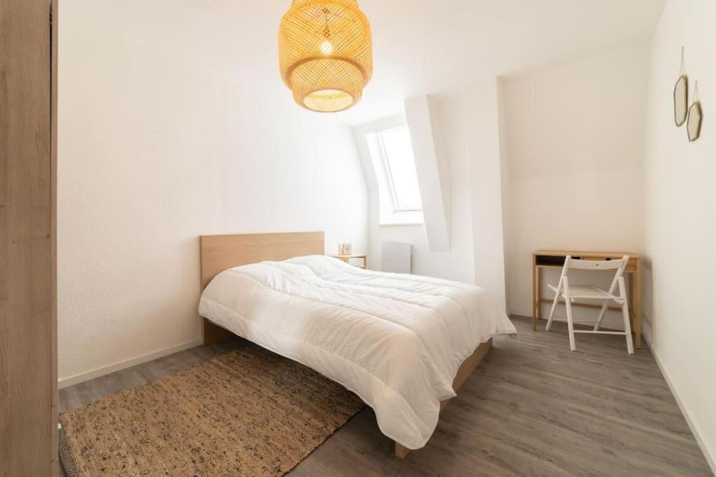 une chambre blanche avec un lit et un bureau dans l'établissement Franklin City, à Mulhouse