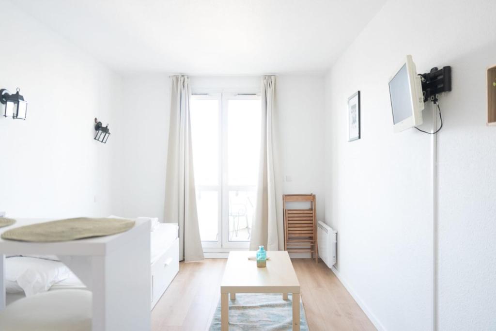 une chambre blanche avec un lit et une table dans l'établissement Charming studio in Saint-Denis, à Saint-Denis