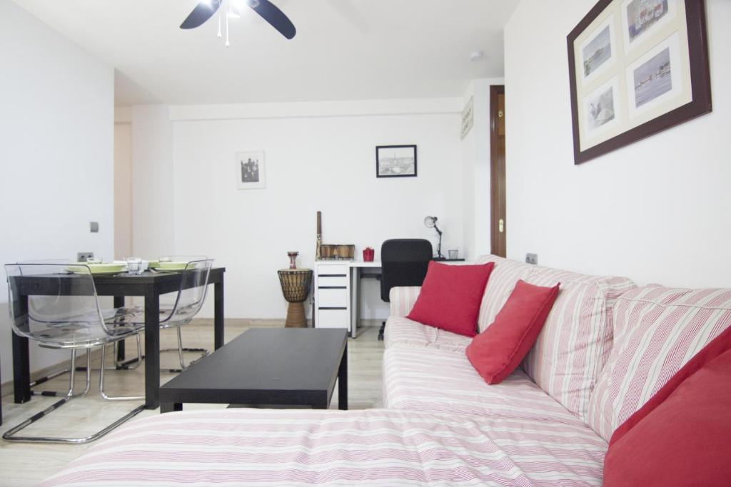una sala de estar con un sofá blanco con almohadas rojas en RentalSevilla Doctor Barraquer, en Sevilla