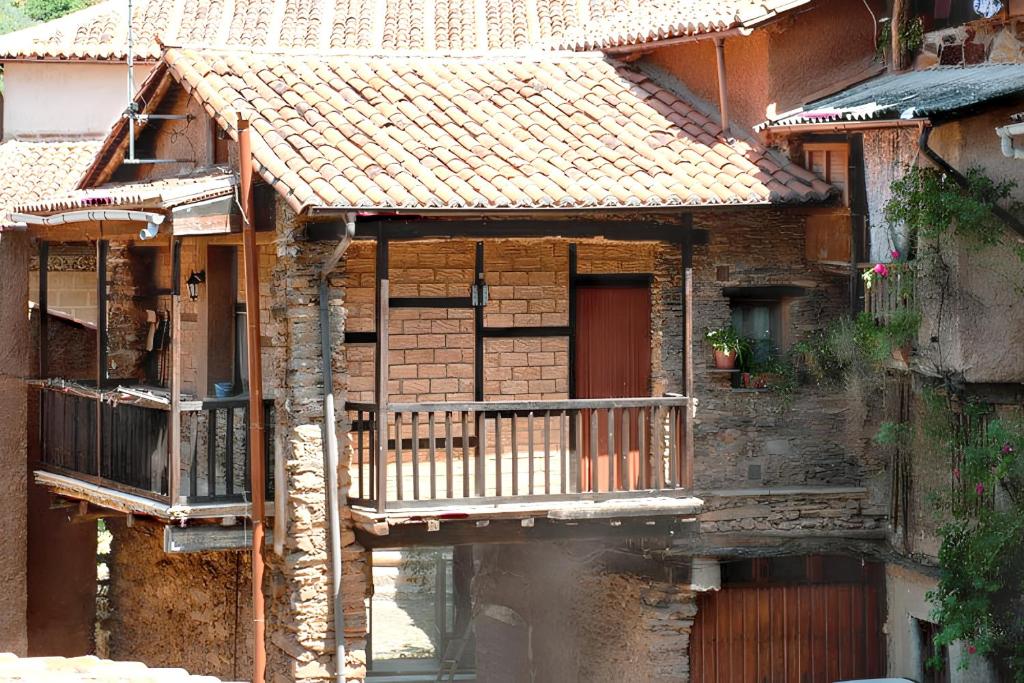 ロブレディージョ・デ・ガタにあるCharming House in Robledillo de Gata with Fireplace and Terraceのポーチとバルコニー付きの古い家