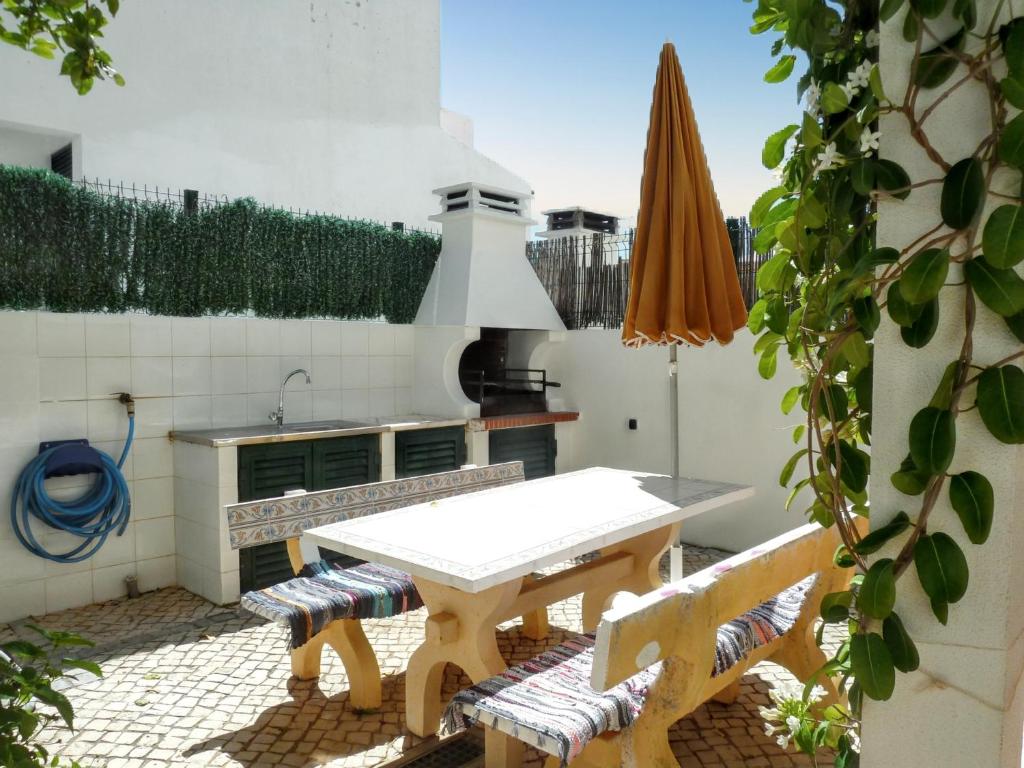a patio with a table and two chairs and an umbrella at Charming house in Vila Nova de Cacela with garden in Vila Nova De Cacela