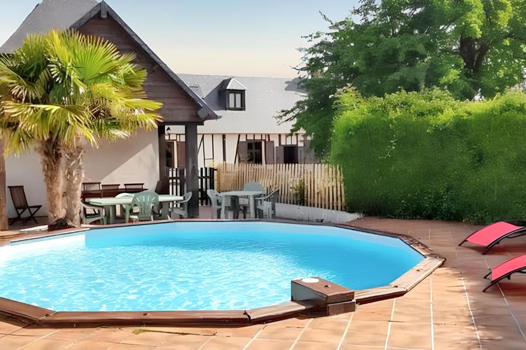 einen großen Pool im Garten mit Tischen und Stühlen in der Unterkunft Villa charmante dans les vergers de Normandie avec piscine privée. in Épinay