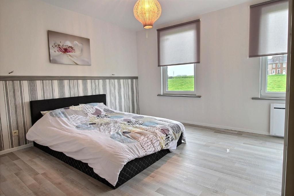 a bedroom with a bed in a room with windows at Gare 84 E Charleroi-airport in Charleroi