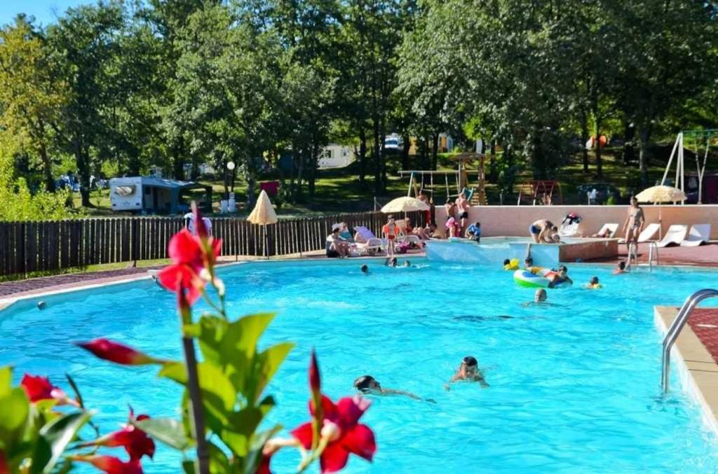 a group of people swimming in a swimming pool at ZEcamping 3 étoiles vue lac environnement calme in Douville