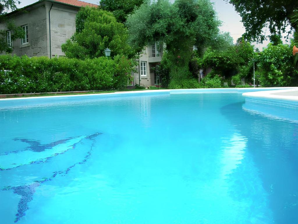 a large pool of blue water in front of a house at Charming villa with mountain view in Pedraça, pool in Pedraça