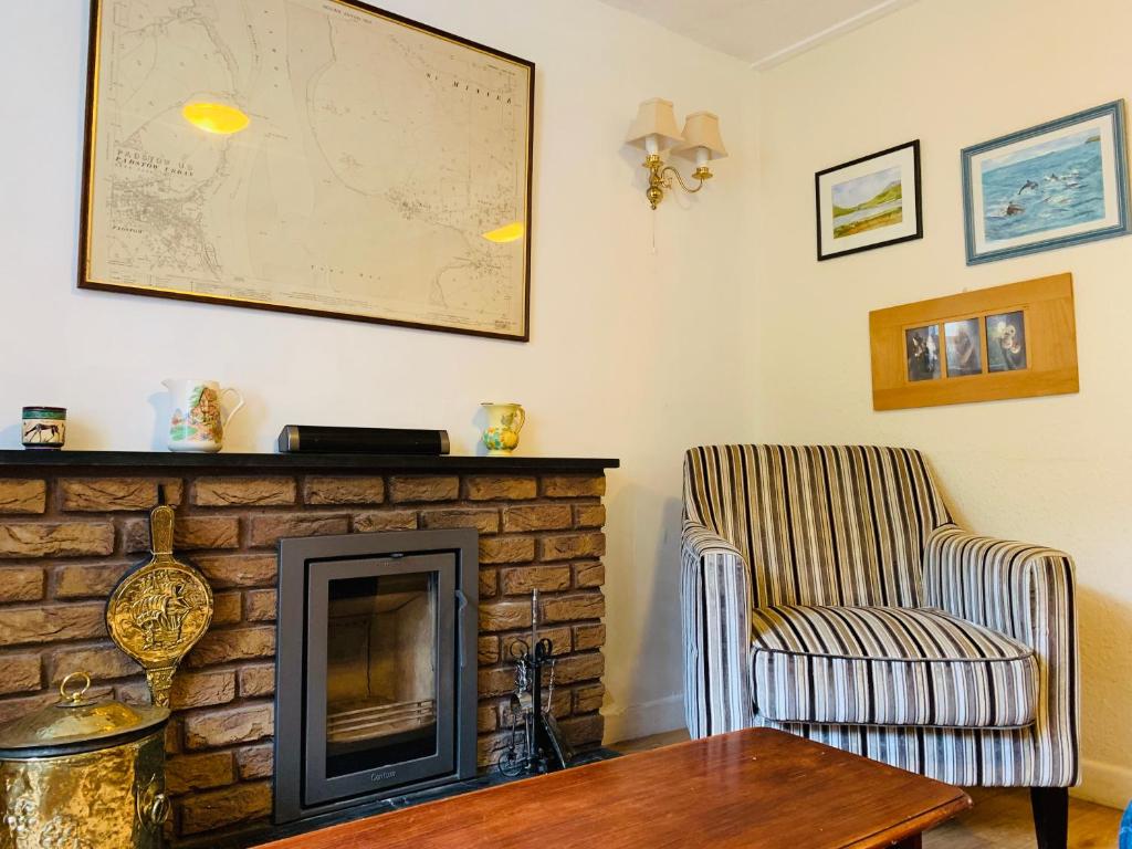 a living room with a fireplace and a chair and a table at Maypole Cottages No 10 Broad Street Padstow in Padstow