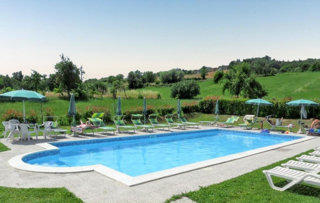 a swimming pool with chairs and umbrellas at Cozy House in Caprese Michelangelo + Pool in Arezzo