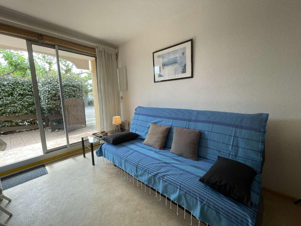- un canapé bleu dans le salon doté d'une fenêtre dans l'établissement Appartement 2 pièces 4 couchages ST CYPRIEN PLAGE SC510-201K, à Saint Cyprien Plage