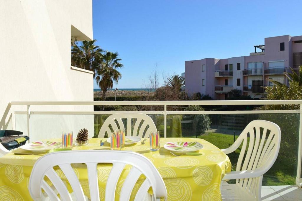 une table et des chaises jaunes sur un balcon dans l'établissement Appartement 2 pièces cabine 6 couchages SAINT CYPRIEN SC050-288A, à Saint Cyprien Plage