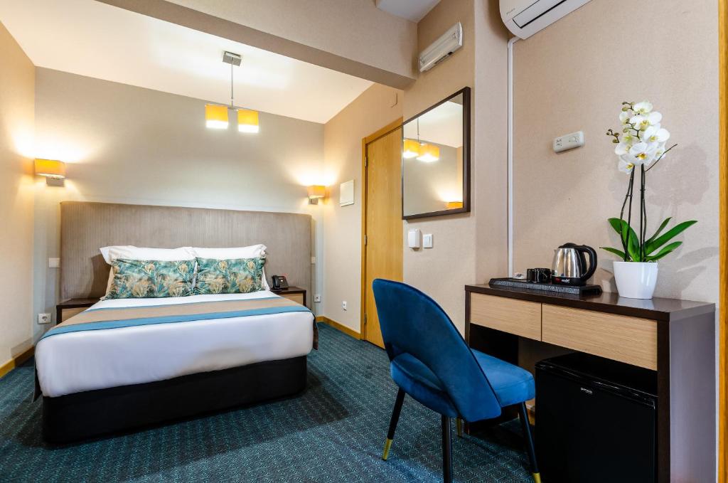 A compact double room with a dedicated desk, blue chair and tea tray.