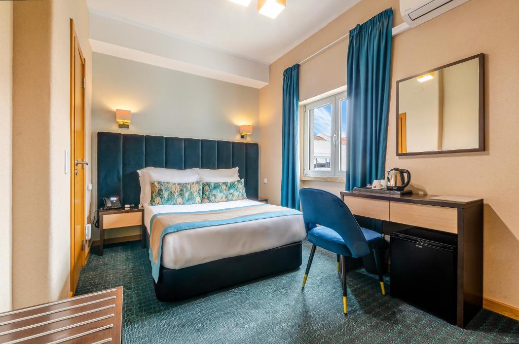 A bedroom includes a narrow desk beside the window and a tea-making setup.