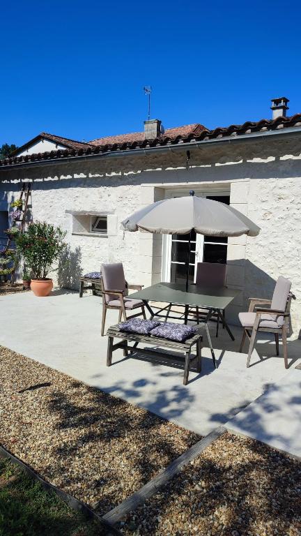 un patio avec une table, des chaises et un parasol dans l'établissement Les Cabrolles, à Saint-Philippe-du-Seignal
