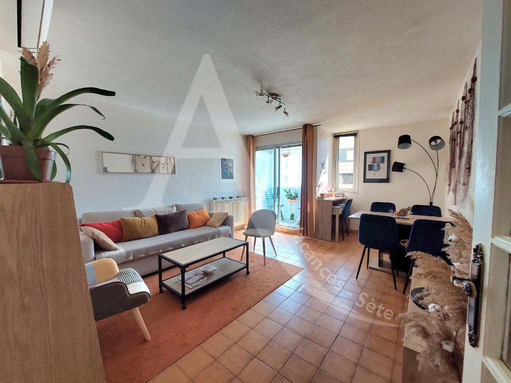 un salon avec un canapé et une table dans l'établissement RDC avec piscine, climatisation et garage, à Sète