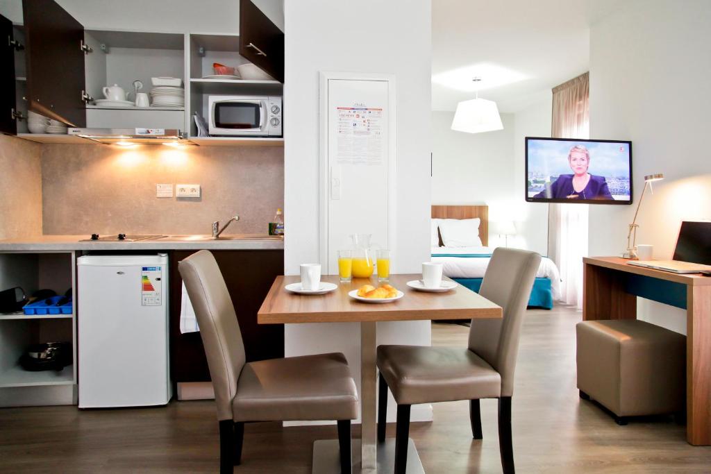 a kitchen and dining room with a table and chairs at Odalys City Tours Le Jardin des Lettres in Tours