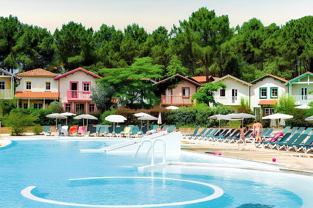 une piscine avec chaises et parasols dans un complexe hôtelier dans l'établissement Maison confortable à Lacanau avec piscine partagée, à Lacanau