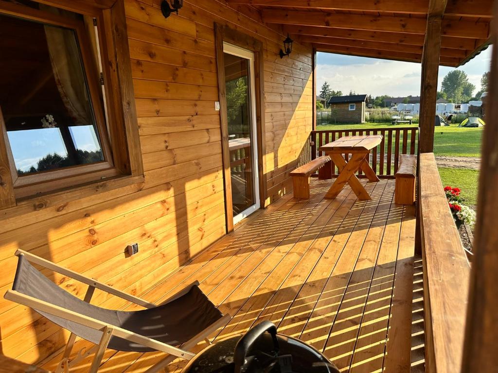 a wooden cabin with a bench and a table on the porch at Domek 4-6osobowy in Wroceń