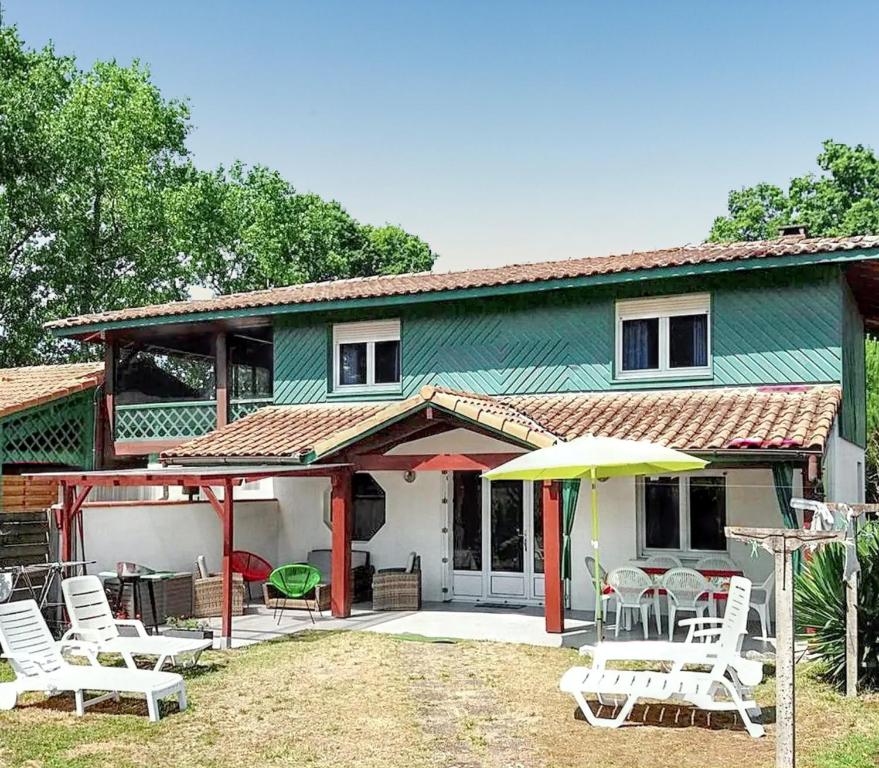 a green house with white chairs and an umbrella at Maison accueillante à Vielle-Saint-Girons avec jardin et cheminée in Vielle-Saint-Girons