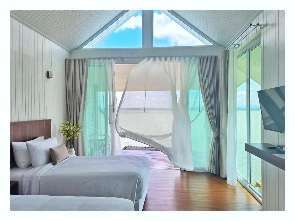ein Schlafzimmer mit zwei Betten und einem großen Fenster in der Unterkunft Sea Balcony Cottage in Satun