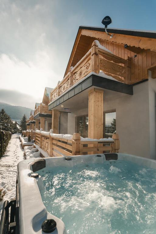a hot tub in front of a house in the snow at Frankowe Domki in Szczawnica