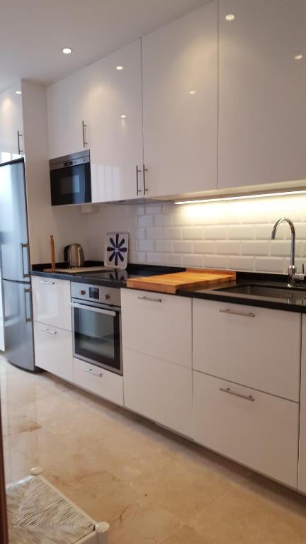 a kitchen with white cabinets and stainless steel appliances at El Capistrano Sur in Nerja