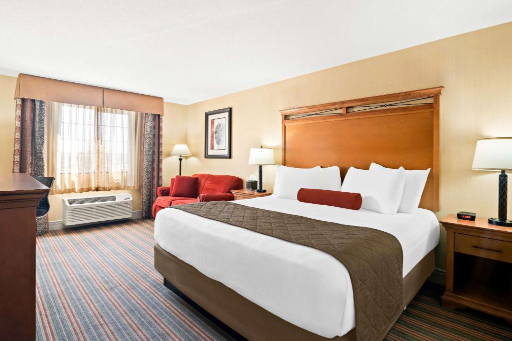 a hotel room with a large bed and a red chair at Best Western Newberry Station in La Pine