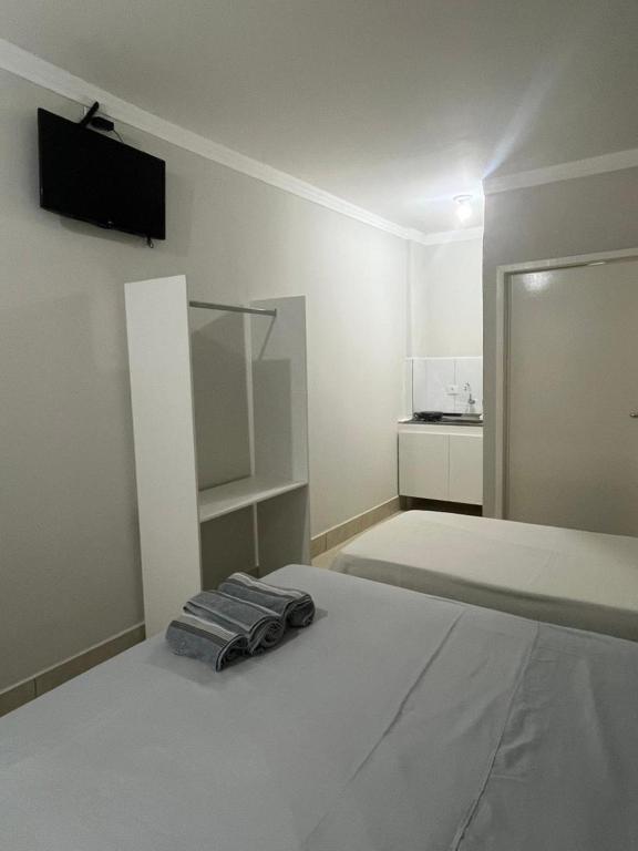 a white bedroom with a bed with a tv on the wall at Studio 38 - Próx ao Parque do Sabiá Aeroporto e Shopping in Uberlândia