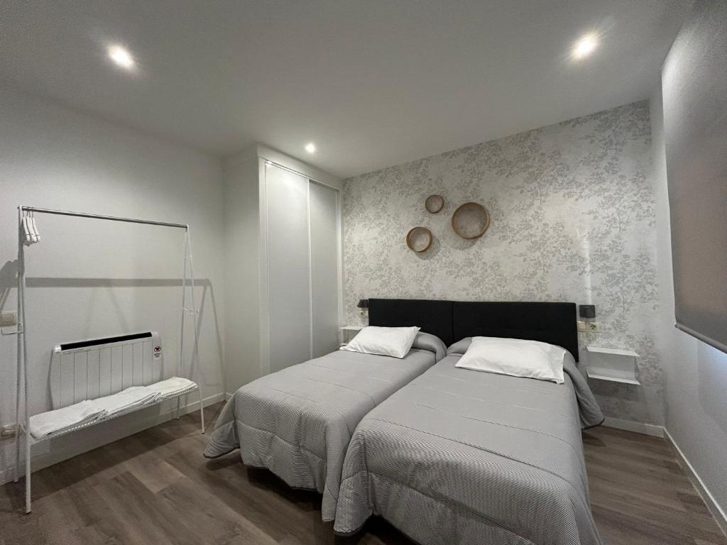 a bedroom with two beds and a wall at Pensión Os Mollados in O Pedrouzo