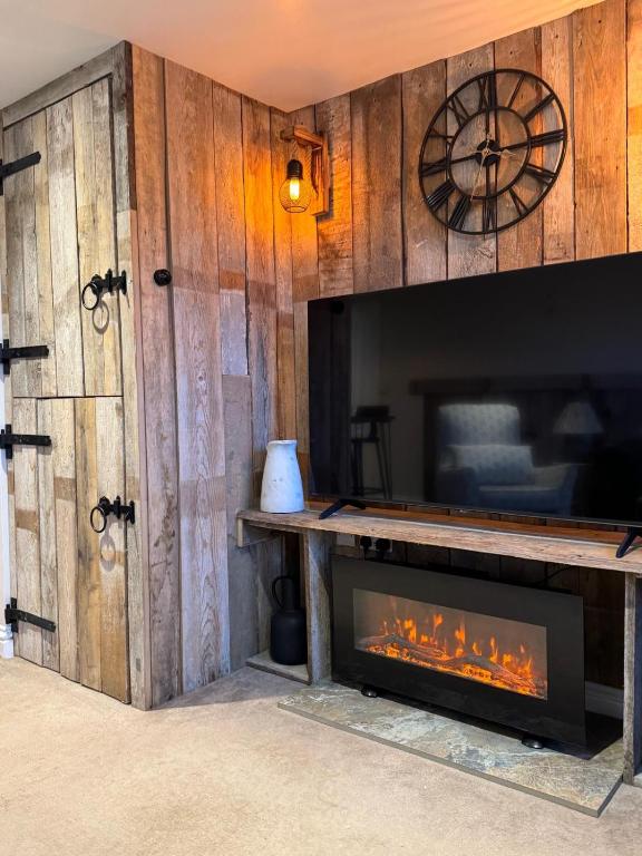 a living room with a fireplace and a clock at Cosy Hideaway 7 min from Soho farmhouse in Enstone