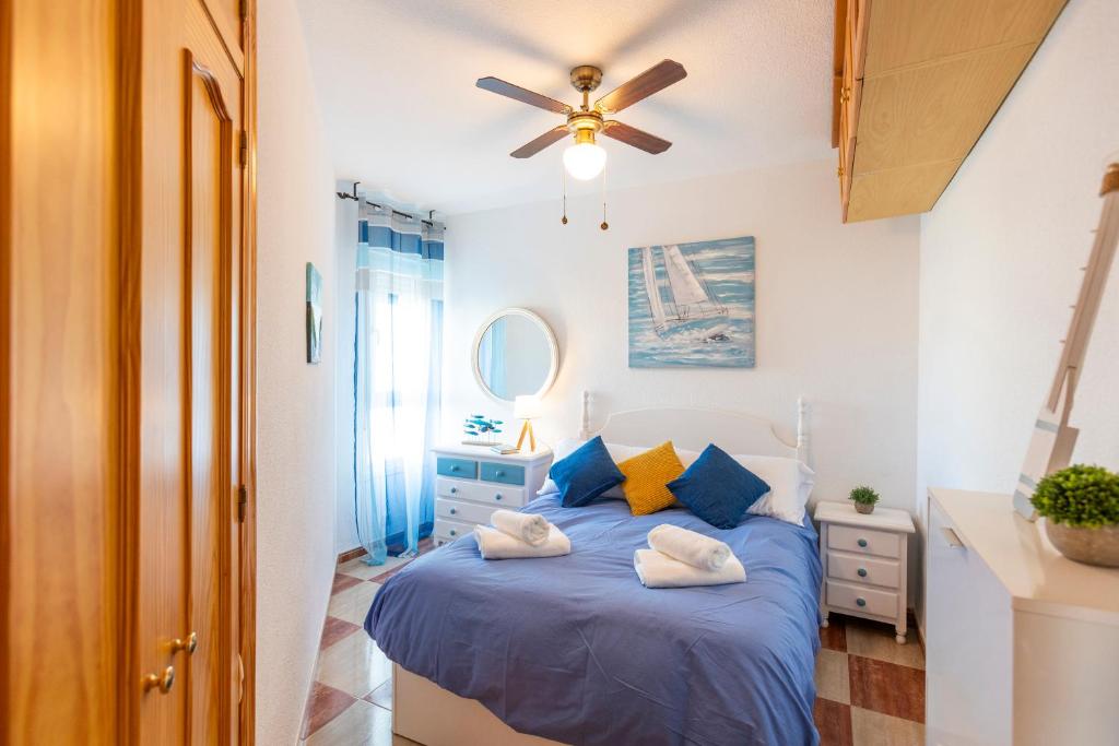 een slaapkamer met een blauw bed en een plafondventilator bij Todimer Ohana Beach in Salobreña